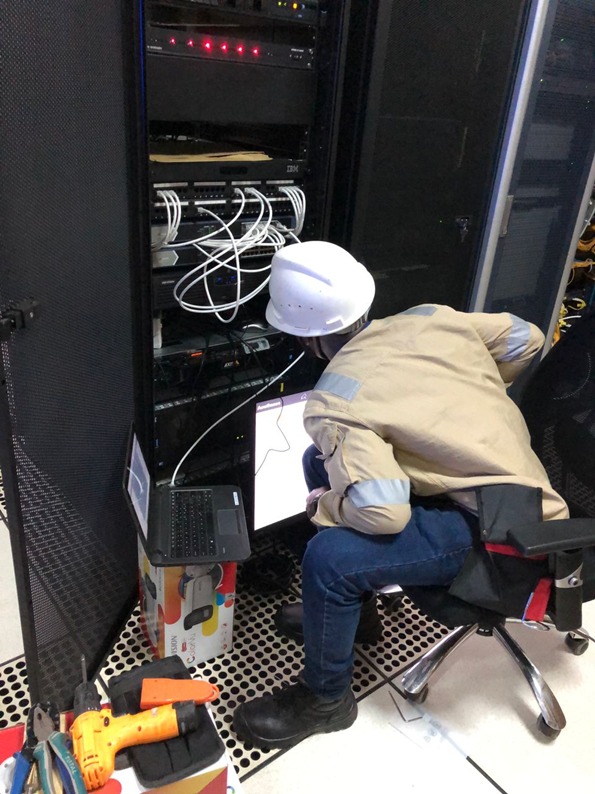 Technician terminating cables at the base of a network server rack